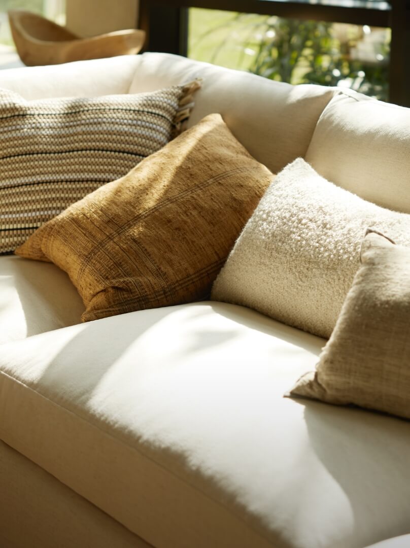 A white couch with colorful pillows placed near a window, creating a cozy and inviting atmosphere.